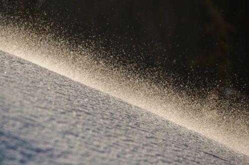 Backlit snow spray blowing off a ridge