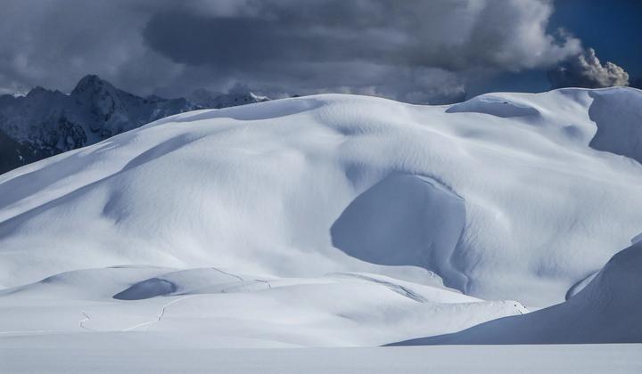 Wind-sculpted snow drifts under storm clouds