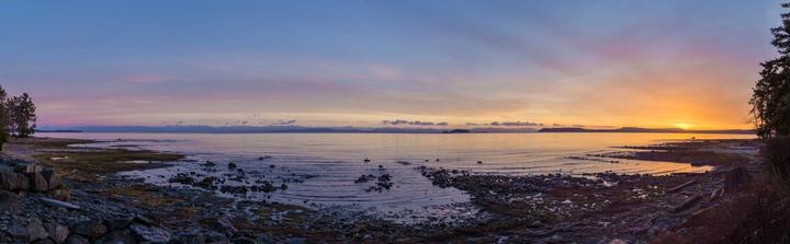 Panoramic coastal sunset over calm water
