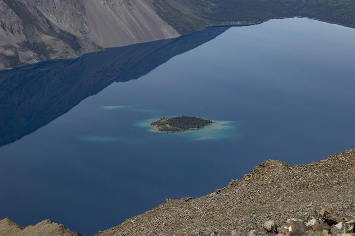 Deep blue lake with a small island below steep slopes